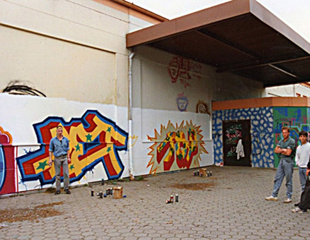 Graffitikurs für das Arbeitsamt Hamburg 1989. Die Kursteilnehmer waren Graffitiinteressierte aus kreativen Berufen mit dem Wunsch Graffiti zu lernen. Leitung Graffitikurs Siko Ortner mit seinem Schüler Wizz. Zunächst wurden die Grundstilrichtungen unterrichtet (Bubble Style, Block Style, Balken Style und Wildstyle), danach kam der Praktische Teil an den Wänden der Rollschuhbahn Indianapolis in Bergedorf Hamburg. Der letzte Tag nach einer Woche Unterricht, kurz vor Abschluss der Pieces.