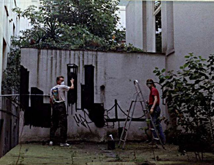 Auftrag Friseur Mertens 1988. Ein Graffitiauftrag für den Friseursalon Mertens in Hamburg, Rothenbaum im August 1988. Auftragsmalerei von der Mad Artists Cooperation, Siko Ortner und seinem Graffitischüler Wizz. Murals in einem Innenhof, piece mit Stancelart/Schablonengraffiti. Wizz und Siko Ortner bei der Arbeit.